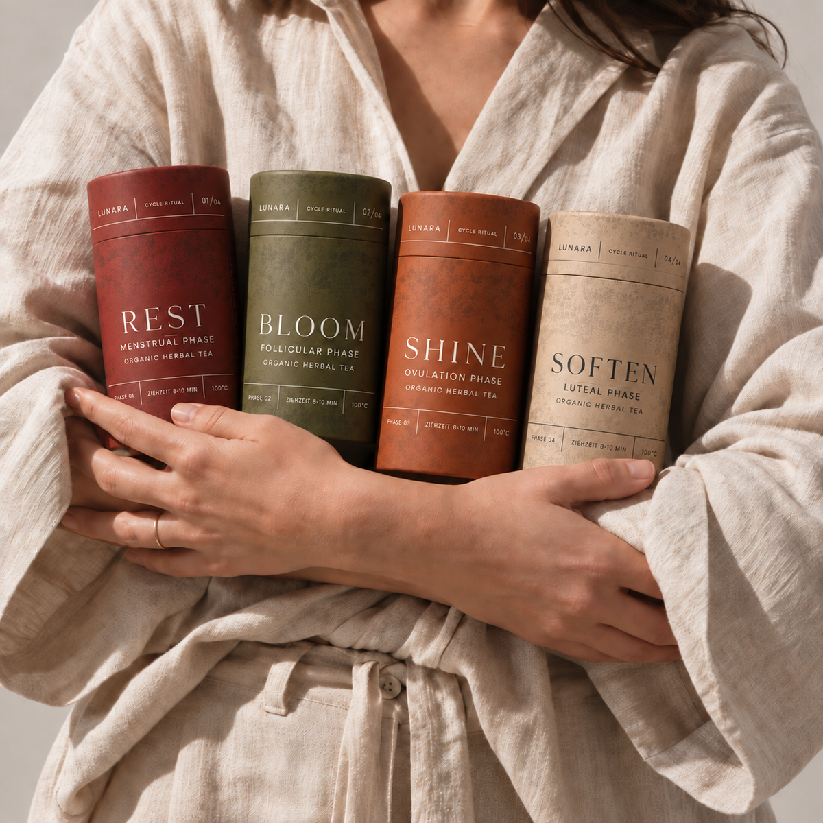 Vier LUNARA Teedosen – REST, BLOOM, SHINE und SOFTEN – in den Händen einer Frau